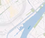 Kort, der viser et udsnit af en by med en flod, der løber igennem den. Åen, mærket "Syvashamnen", er omgivet af gader og bygninger på begge sider. En bro krydser floden og der er et grønt område til højre.
